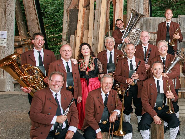 Ein Teil der Musiker sitzt und steht lachend vor der Kamera mit ihren Instrumenten in den Händen.
