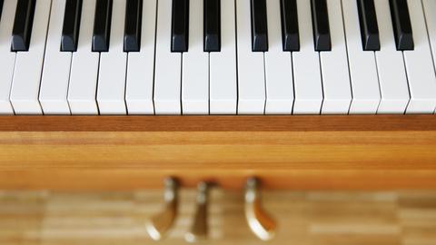 Klaviertasten von oben fotografiert, schemenhaft sind noch die Pedale zu sehen