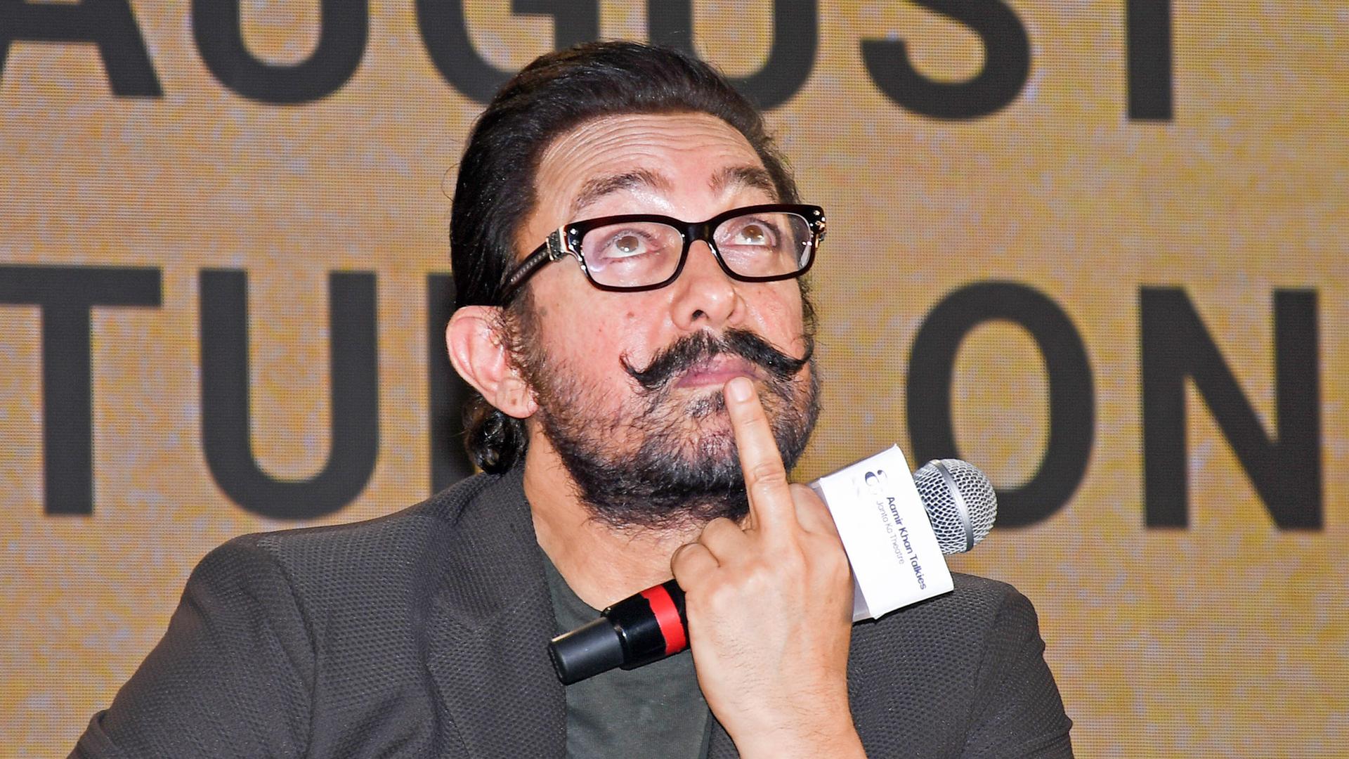 Der Bollywood-Schauspieler Aamir Khan hält ein Mikro in der Hand und guckt nach oben.