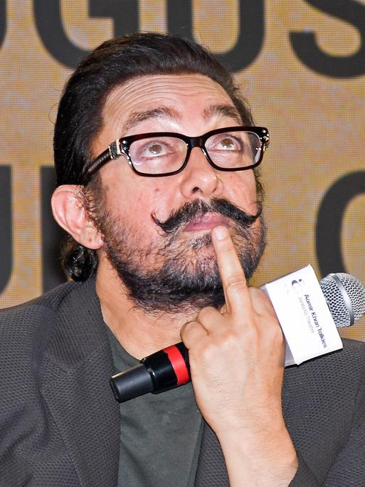 Der Bollywood-Schauspieler Aamir Khan hält ein Mikro in der Hand und guckt nach oben.