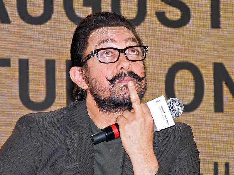 Der Bollywood-Schauspieler Aamir Khan hält ein Mikro in der Hand und guckt nach oben.