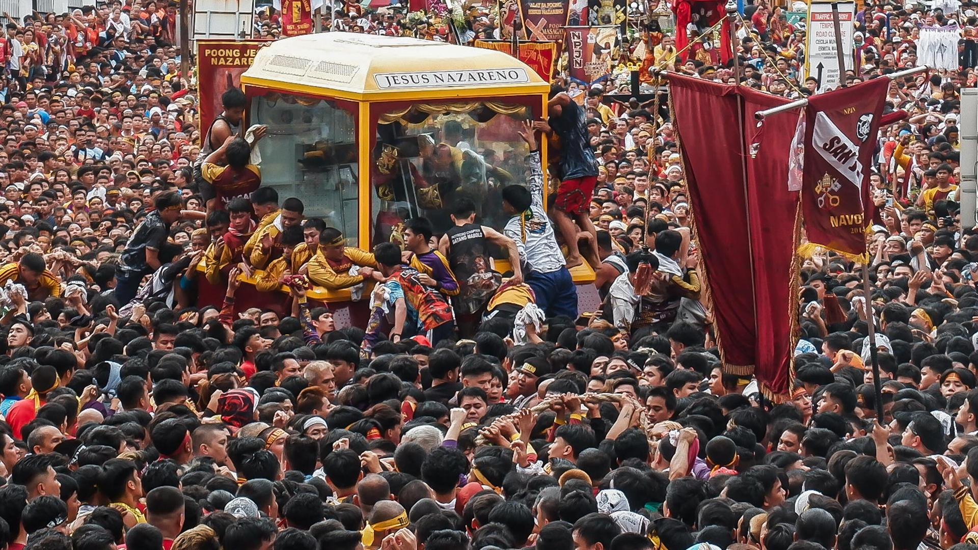Viele Gläubige in Manila stehen um einen Glaskasten, in dem eine Statue zu sehen ist.