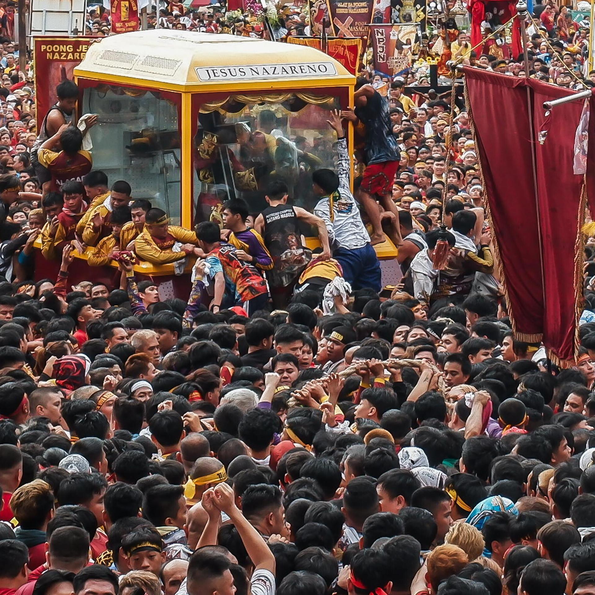 Viele Gläubige in Manila stehen um einen Glaskasten, in dem eine Statue zu sehen ist.