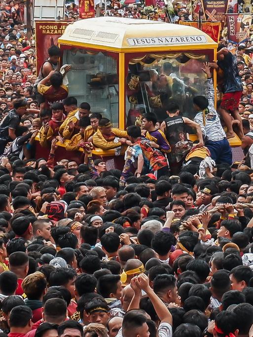 Viele Gläubige in Manila stehen um einen Glaskasten, in dem eine Statue zu sehen ist.