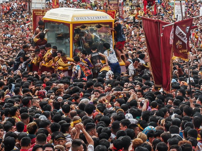 Viele Gläubige in Manila stehen um einen Glaskasten, in dem eine Statue zu sehen ist.