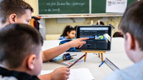 Kinder einer vierten Klasse arbeiten im Unterricht mit einem Tablet