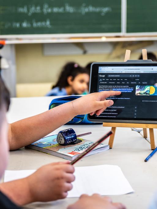 Kinder einer vierten Klasse arbeiten im Unterricht mit einem Tablet