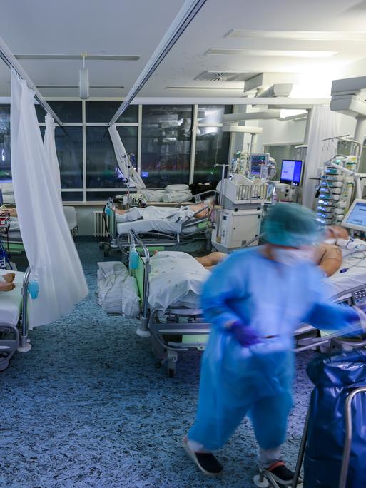 Eine Intensivpflegerin versorgt einen Covid-19-Patienten auf der Intensivstation der Leipziger Uniklinik in einem Zimmer, in dem noch drei weitere Corona-Patienten liegen.
