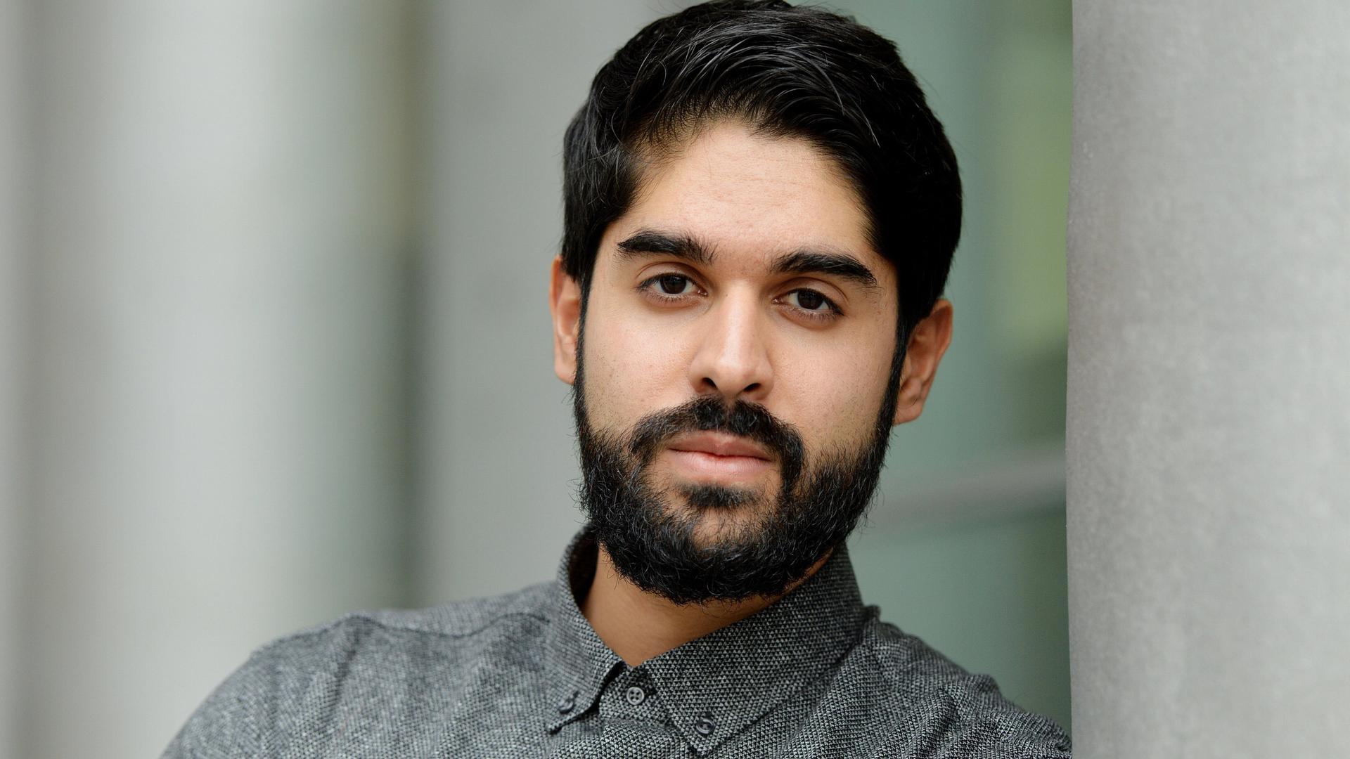 Emran Feroz schaut in die Kamera. Er trägt dunkles Haar mit einem gestutzten Vollbart und ein graues Kragenhemd. Emran Feroz schaut in die Kamera. Er trägt dunkles Haar mit einem gestutzten Vollbart und ein graues Kragenhemd.
