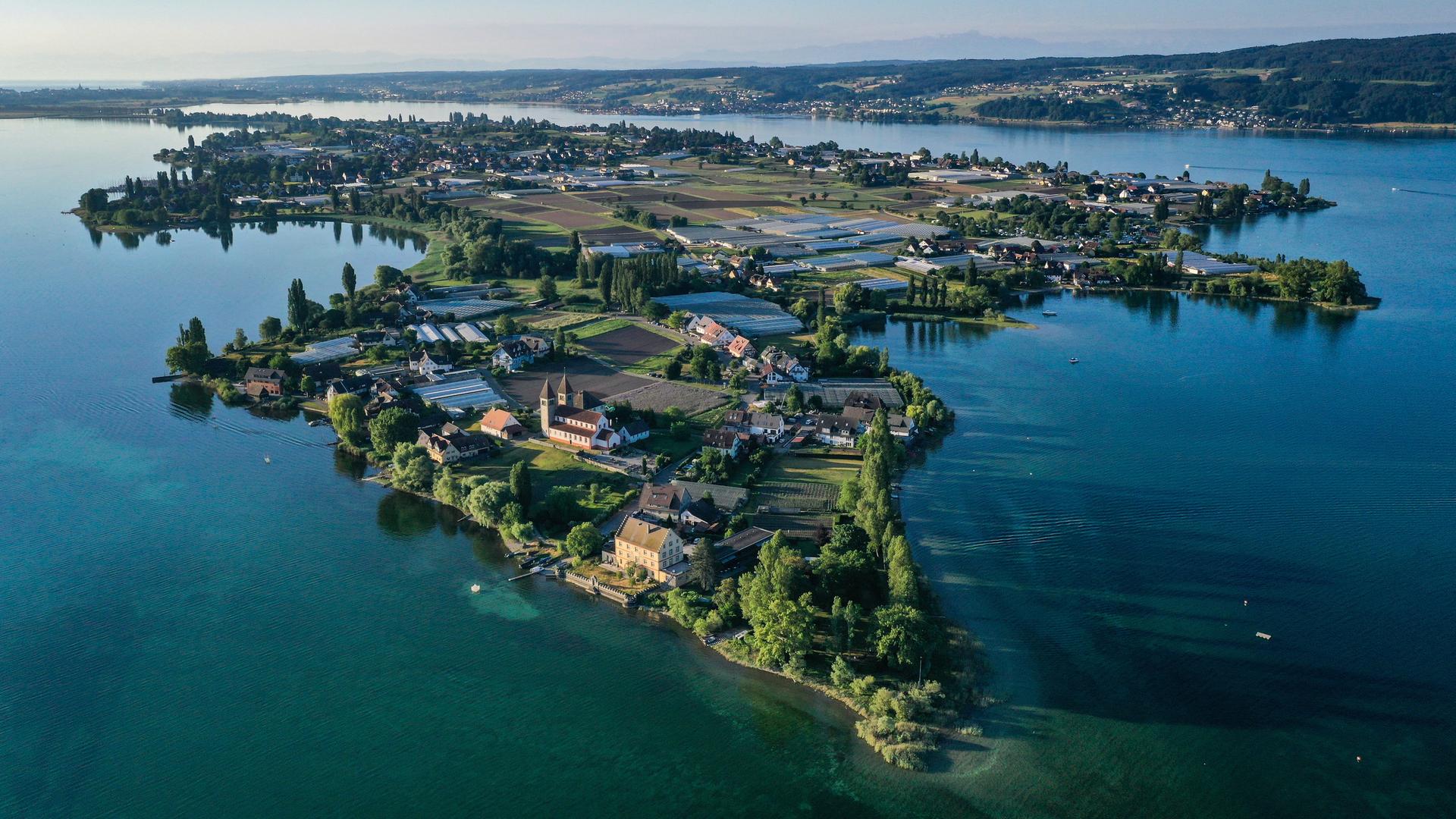 Die aufgehende Sonne strahlt die romanische Säulenbasilika, St. Peter und Paul, auf der Insel Reichenau an. Aufnahme mit Drohne.