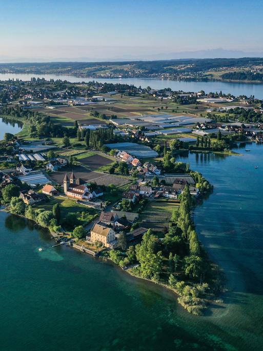 Die aufgehende Sonne strahlt die romanische Säulenbasilika, St. Peter und Paul, auf der Insel Reichenau an. Aufnahme mit Drohne.