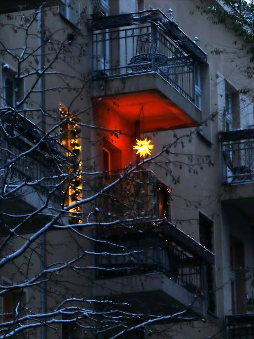 Leuchtender Weihnachtsstern - Berlin, Deutschland, DEU, GER, 09.12.2021 - Berlin-Mitte: Weihnachtsstern leuchtet in der Adventszeit an einem Balkon einer Altbaufassade in den Abendhimmel. *** Shining Christmas star Berlin, Germany, DEU, GER, 09 12 2021 Berlin Mitte Christmas star shines in the Advent season on a balcony of an old building facade into the evening sky