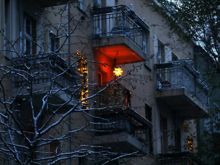 Leuchtender Weihnachtsstern - Berlin, Deutschland, DEU, GER, 09.12.2021 - Berlin-Mitte: Weihnachtsstern leuchtet in der Adventszeit an einem Balkon einer Altbaufassade in den Abendhimmel. *** Shining Christmas star Berlin, Germany, DEU, GER, 09 12 2021 Berlin Mitte Christmas star shines in the Advent season on a balcony of an old building facade into the evening sky