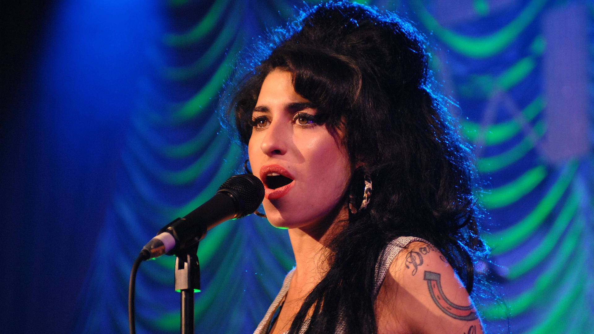 Amy Winehouse singt während eines Auftritts ins Mikrofon.