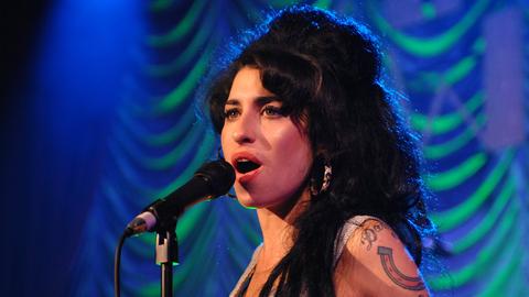 Amy Winehouse singt während eines Auftritts ins Mikrofon.