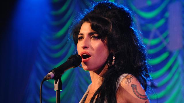 Amy Winehouse singt während eines Auftritts ins Mikrofon.