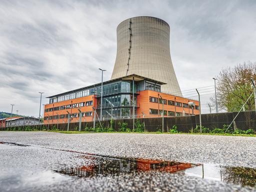 Der Kühlturm des stillgelegte Kernkraftwerks Isar 2. Davor ein orangefarbenes Gebäude.