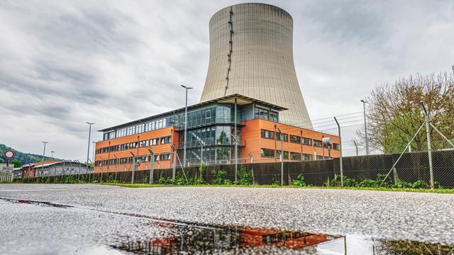 Der Kühlturm des stillgelegte Kernkraftwerks Isar 2. Davor ein orangefarbenes Gebäude.