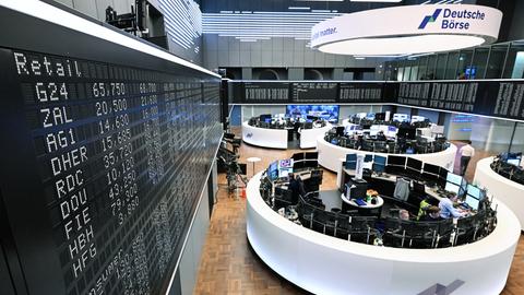 Händler an der Börse in Frankfurt am Main. Zu sehen ist auch eine Anzeigetafel, auf der die Werte des deutschen Aktienindex DAX zu sehen sind.