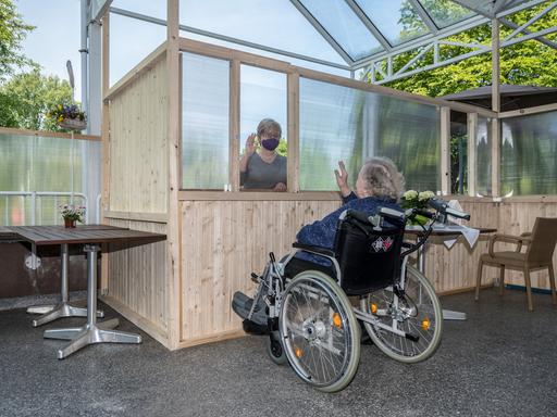 Barbara Fabian besucht am Freitag, 08.05.2020, ihre 87-jährige Mutter Irene Termin im Franziskushaus in Mülheim an der Ruhr. Dabei sind die beiden auf der Terrasse des Hauses durch einen Holzzaun und Plexiglasscheiben getrennt.