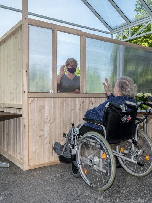 Barbara Fabian besucht am Freitag, 08.05.2020, ihre 87-jährige Mutter Irene Termin im Franziskushaus in Mülheim an der Ruhr. Dabei sind die beiden auf der Terrasse des Hauses durch einen Holzzaun und Plexiglasscheiben getrennt.