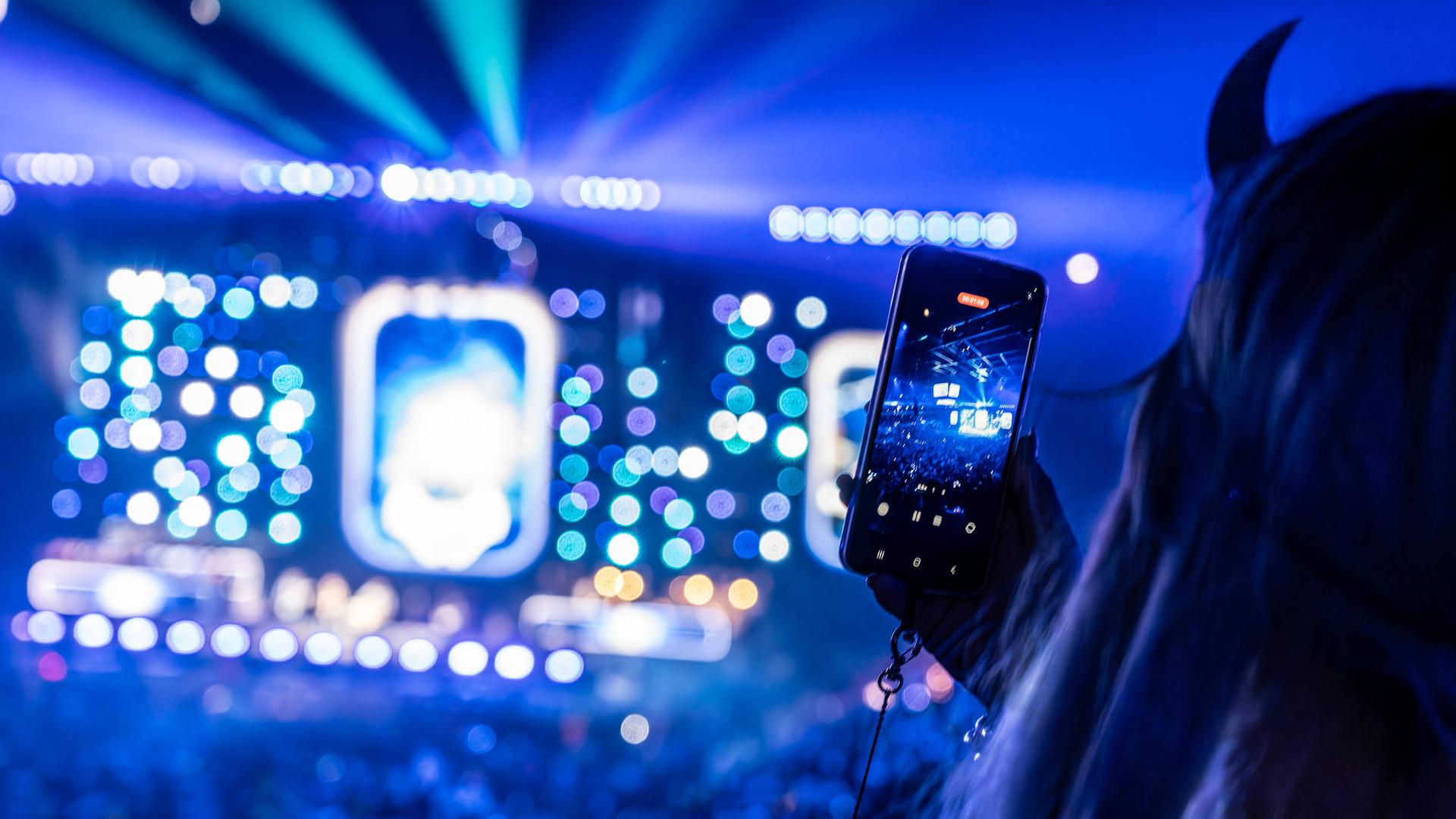 Eine Zuschauerin filmt mit ihrem Smartphone die Bühne bei einem Konzert im Düsseldorfer Stadion