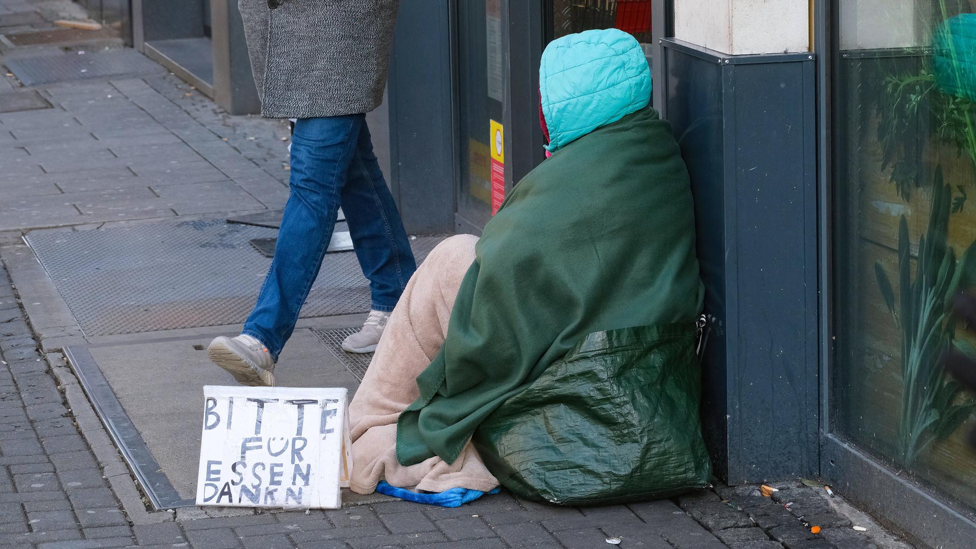 Eine Obdachlose sitzt in Düsseldorf auf der Straße