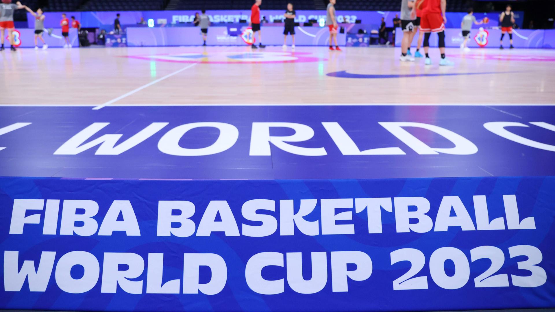 Das Logo der Basketball-WM in Japan in einer Halle. Oberhalb sieht man das Spielfeld mit Spielern.
