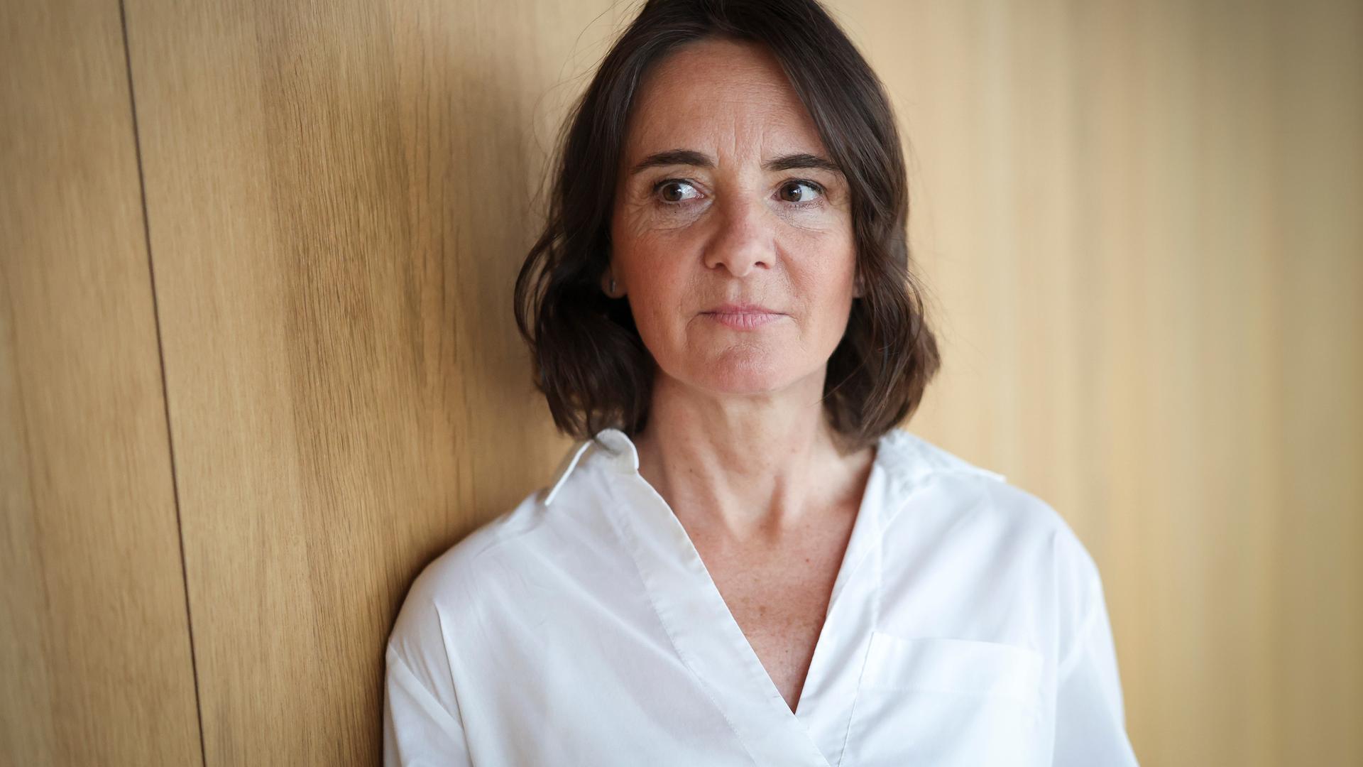 Martina Heßler mit weißer Bluse und dunklen Haaren steht vor einer Wand aus Holz und schaut zur Seite Martina Heßler mit weißer Bluse und dunklen Haaren steht vor einer Wand aus Holz und schaut zur Seite