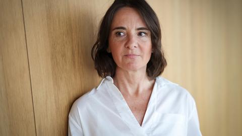 Martina Heßler mit weißer Bluse und dunklen Haaren steht vor einer Wand aus Holz und schaut zur Seite Martina Heßler mit weißer Bluse und dunklen Haaren steht vor einer Wand aus Holz und schaut zur Seite