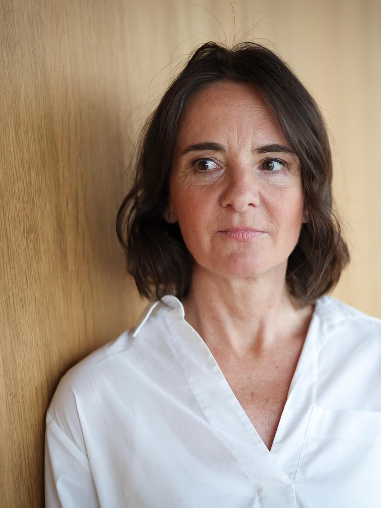 Martina Heßler mit weißer Bluse und dunklen Haaren steht vor einer Wand aus Holz und schaut zur Seite