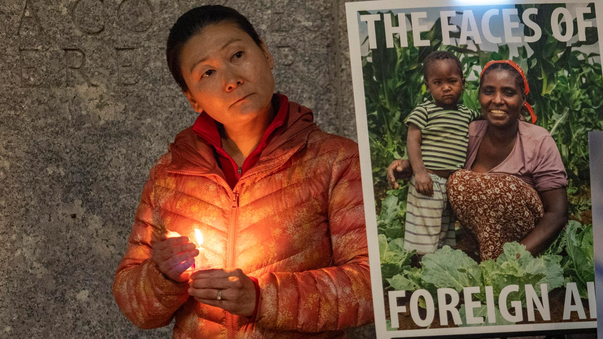 Eine Frau demonstriert in Washington D.C. mit einer Kerze in der Hand vor einem Plakat gegen die Kürzungen der Auslandshilfe USAID.