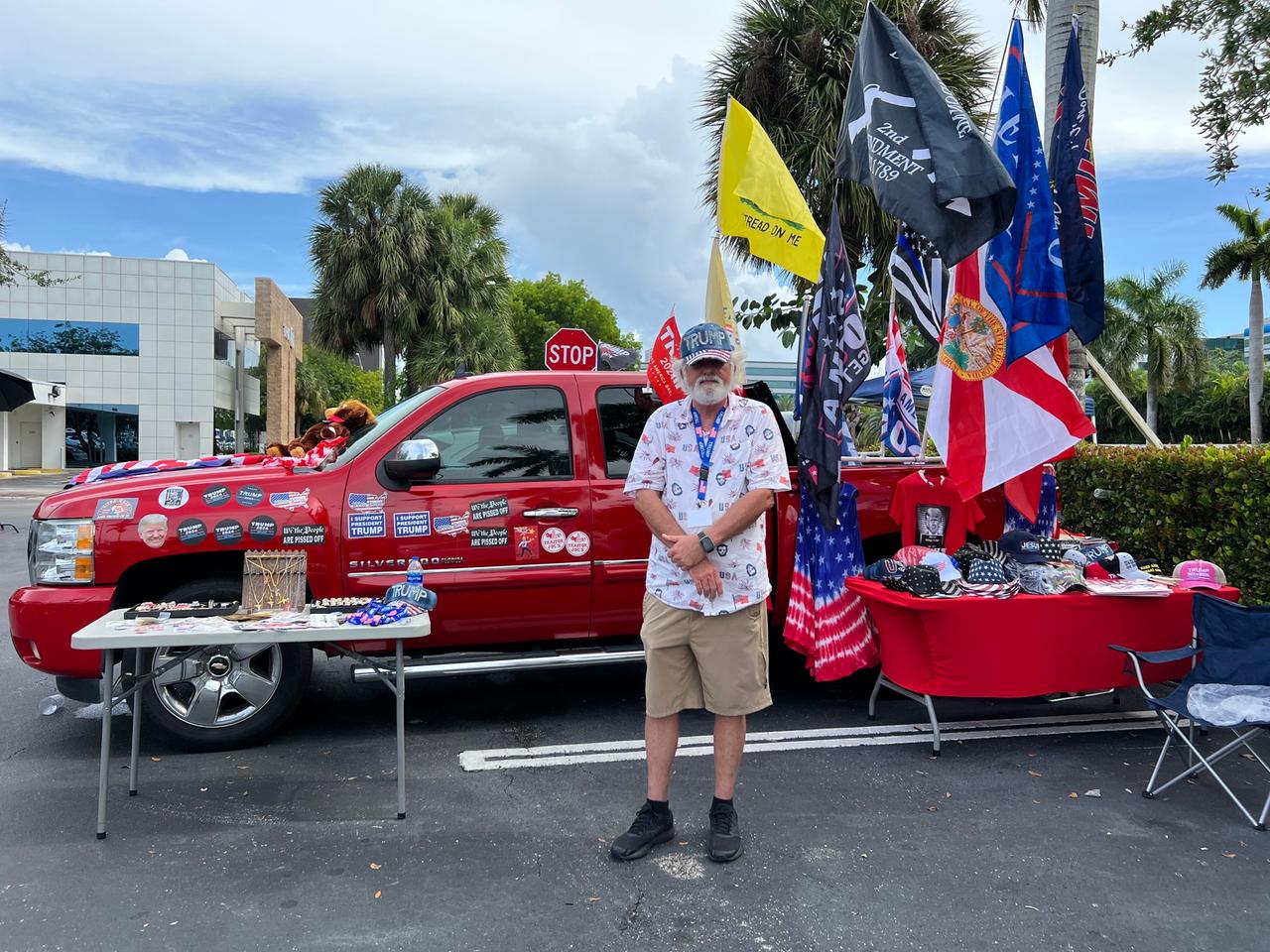Ein Trump-Anhänger steht in Miami vor seinem roten, mit Stickern beklebten Auto.