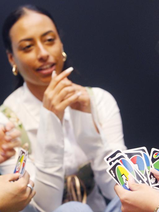 Fachbesucher und Fachbesucherinnen spielen das Kartenspiel "UNO all wild!".