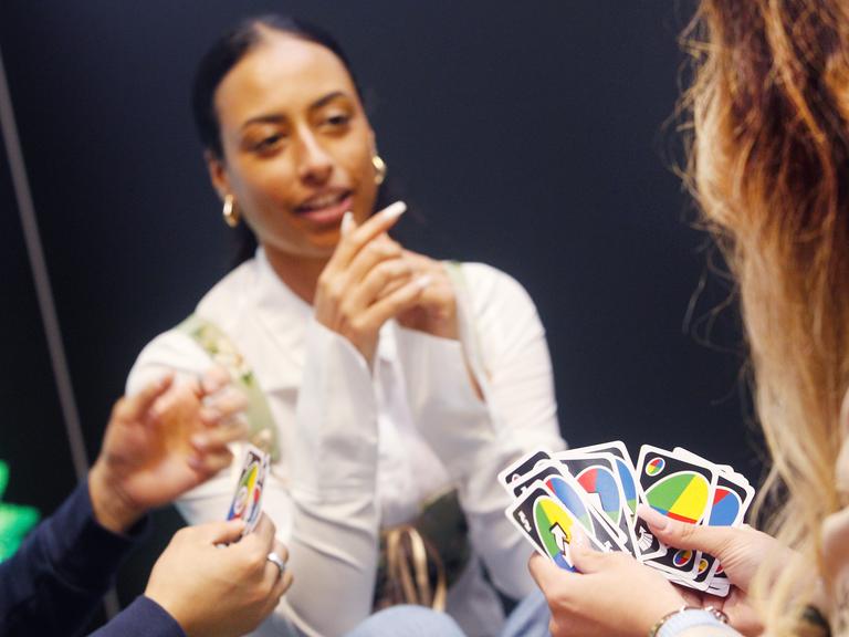 Fachbesucher und Fachbesucherinnen spielen das Kartenspiel "UNO all wild!".
