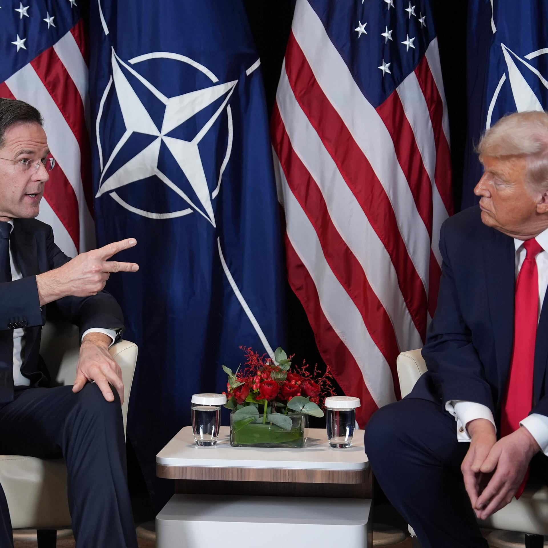 US-Präsident Trump und NATO-Generalsekretär Rutte bei einem Treffen am Rande des Weltwirtschaftsforums in Davos. Beide sitzen auf Sesseln und schauen sich an. Rutte gestikuliert. Hinter ihnen sind die amerikanische und die NATO-Flagge zu sehen.