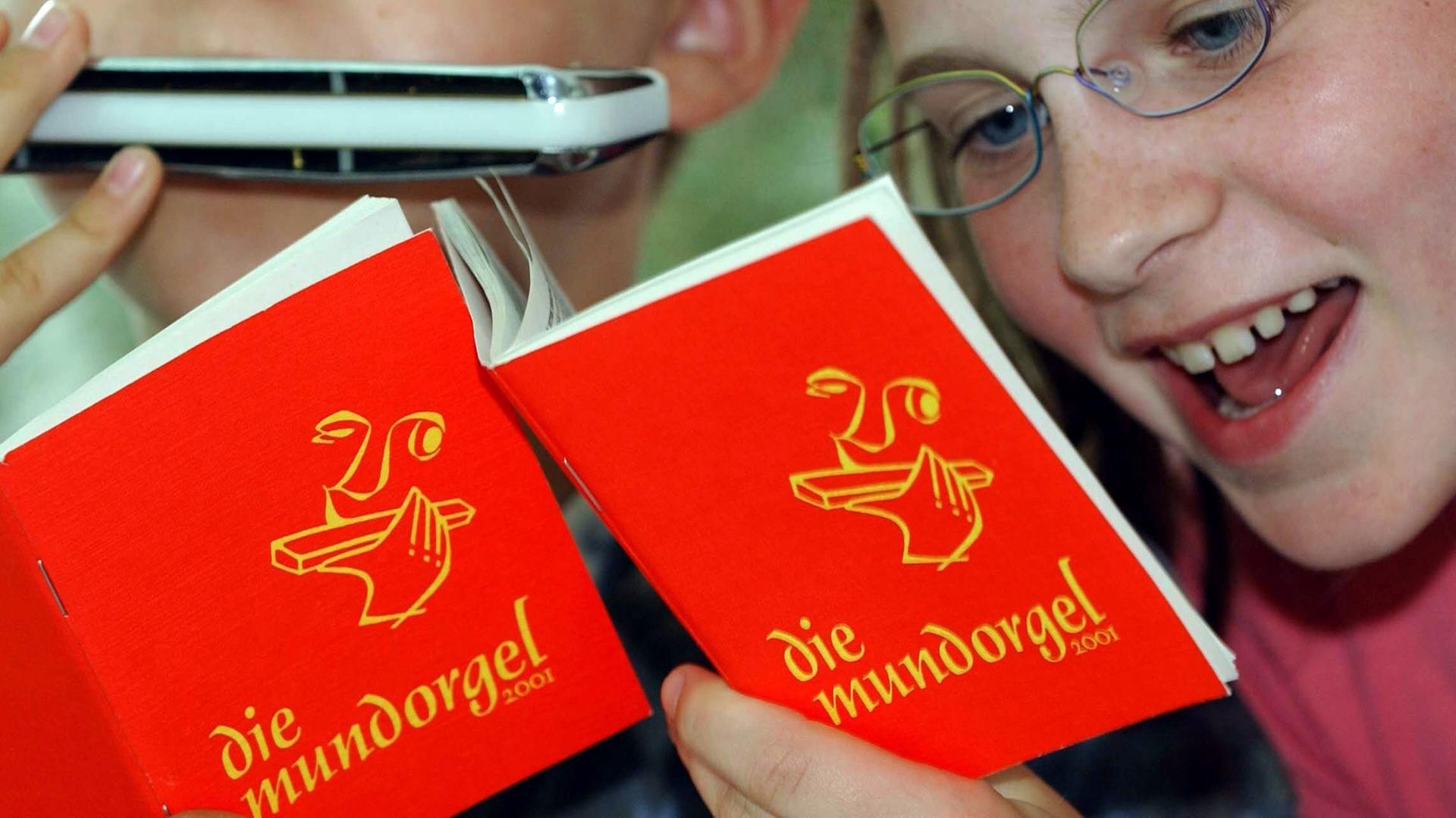 Ein Mädchen singt und ein Junge spielt mit der Mundharmonika Lieder aus der "Mundorgel".
