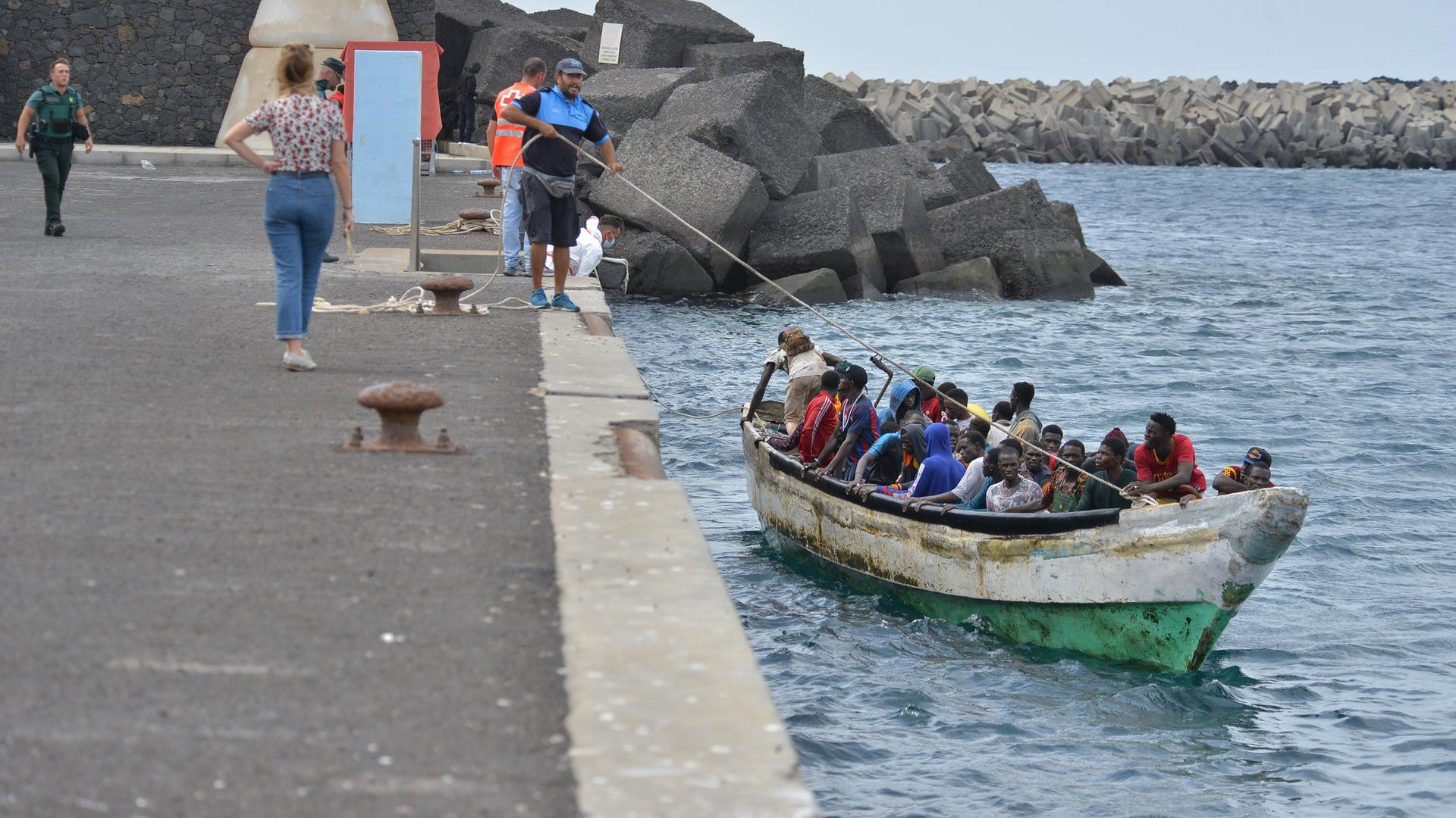 Migranten kommen in einem kleinen Holzboot im Hafen von La Restinga auf der Insel El Hierro an.