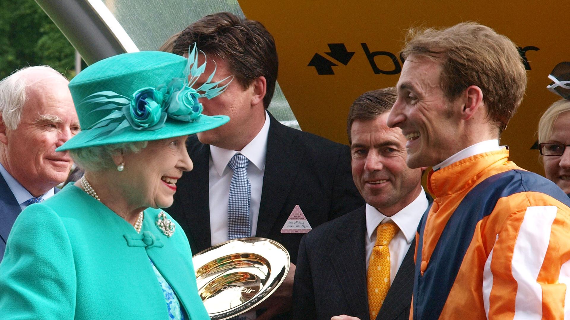 Queen Elizabeth II unterhält sich bei der Siegerehrung mit dem Deutschen Jockey Andrasch Starke beim Pferderennen in Ascot 2012. 