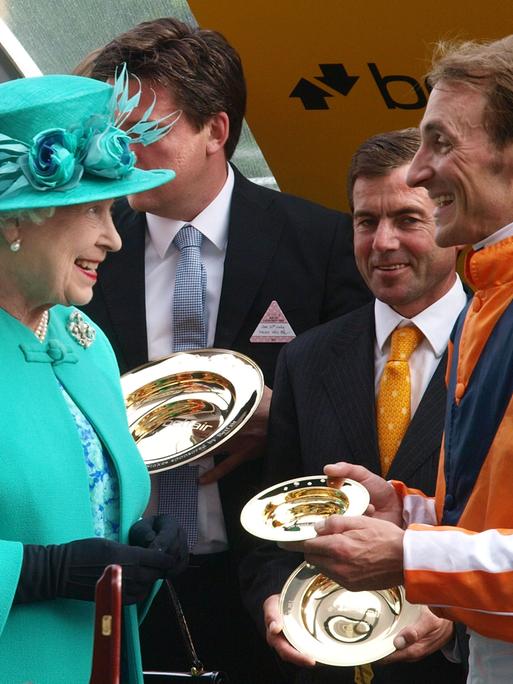 Queen Elizabeth II unterhält sich bei der Siegerehrung mit dem Deutschen Jockey Andrasch Starke beim Pferderennen in Ascot 2012. 