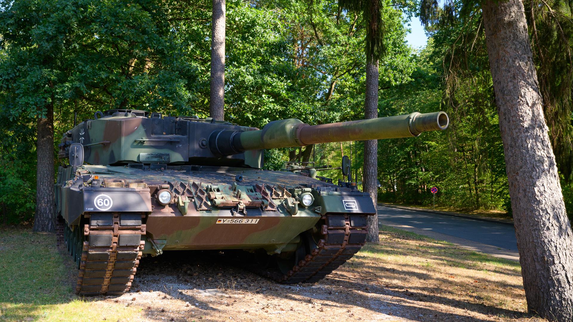 Ein Kampfpanzer des Bundeswehr vom Typ Leopard 2A4 steht in einem Waldstück.