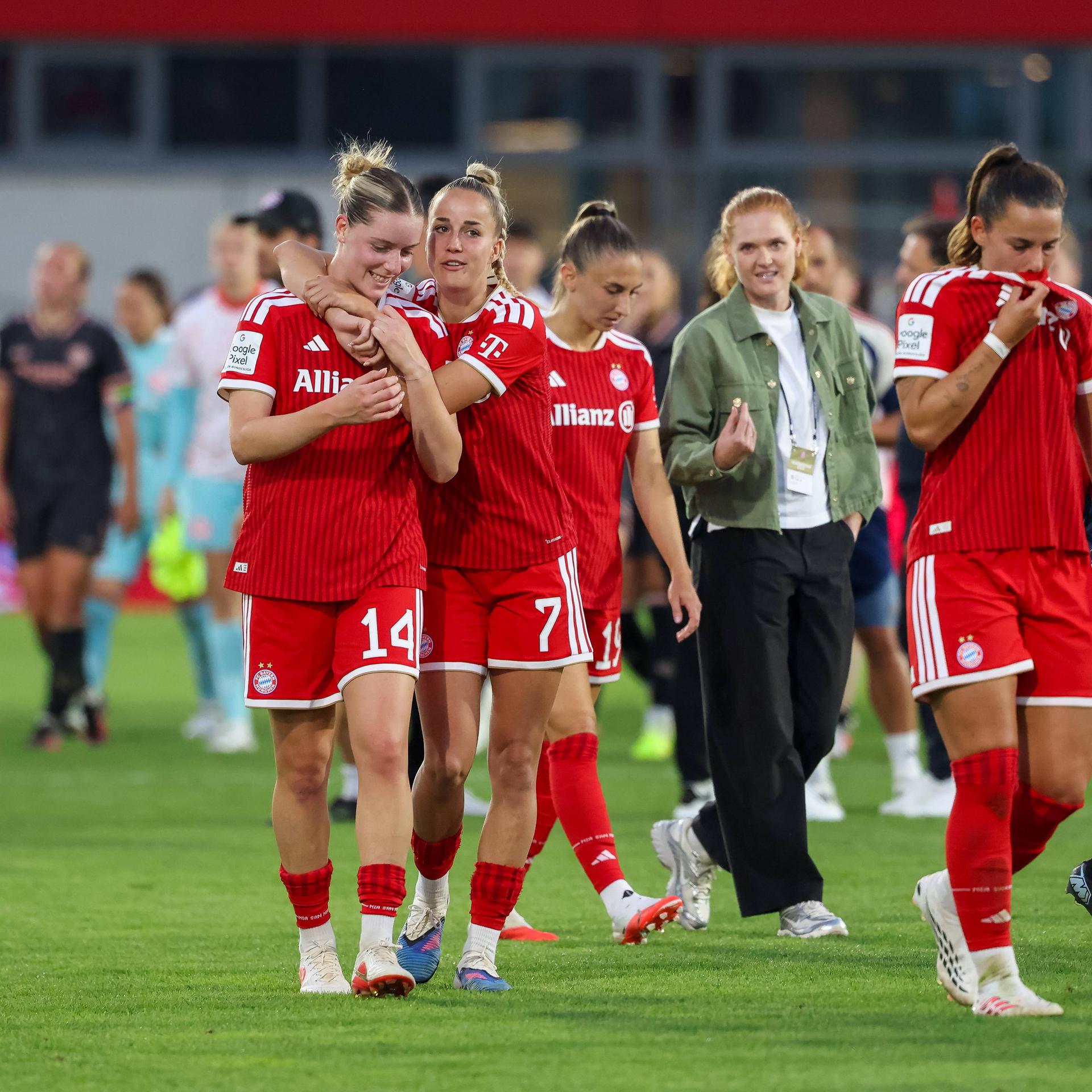 Giulia Gwinn mit Alara Sehitler und weiteren Spielerinnen auf dem Spielfeld. Sie freuen sich.