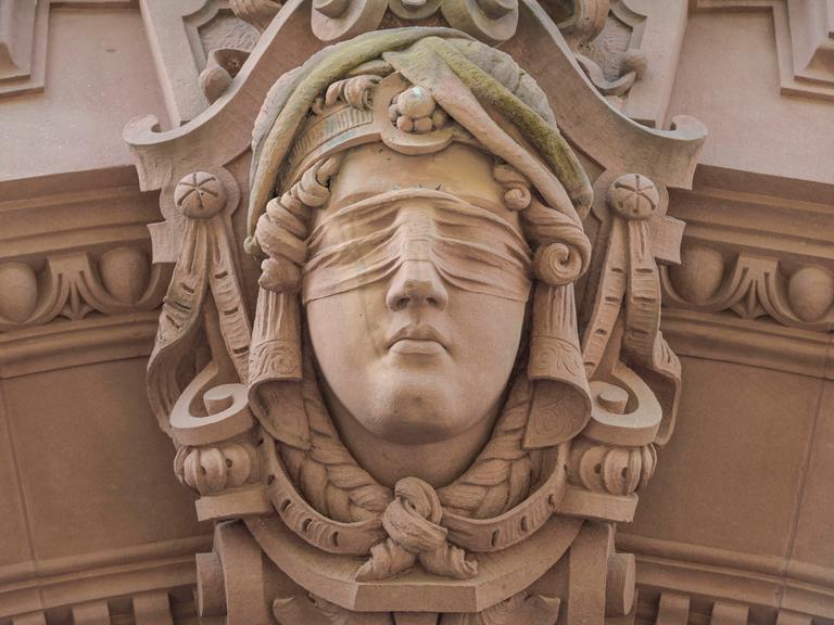 Am Alten Gericht in Wiesbaden hängt eine Sandstein-Skulptur von Justitia, das Abbild einer Frau mit verbundenen Augen