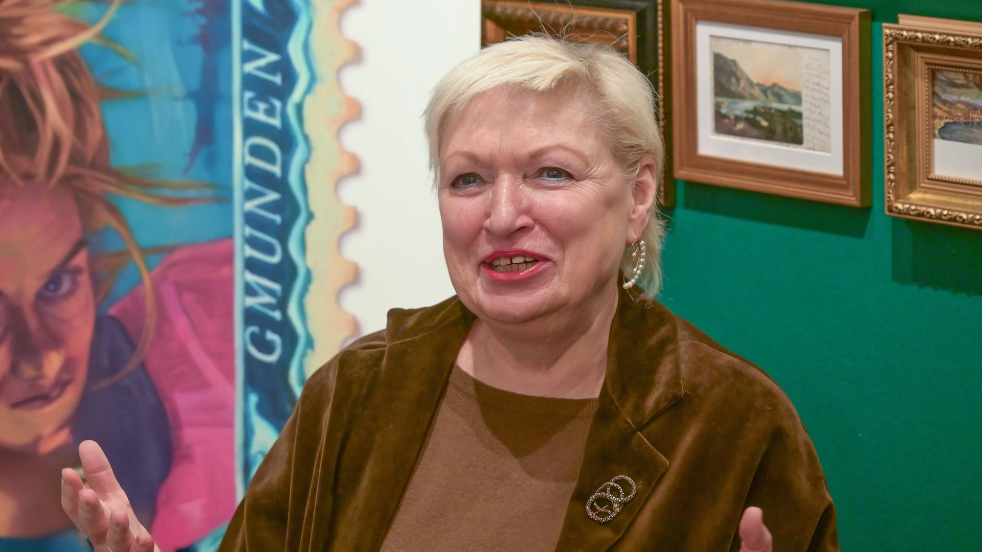 Karin Bergmann breitet die Hände aus und lächelt in die Kamera.