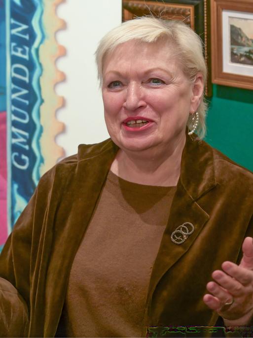 Karin Bergmann breitet die Hände aus und lächelt in die Kamera.