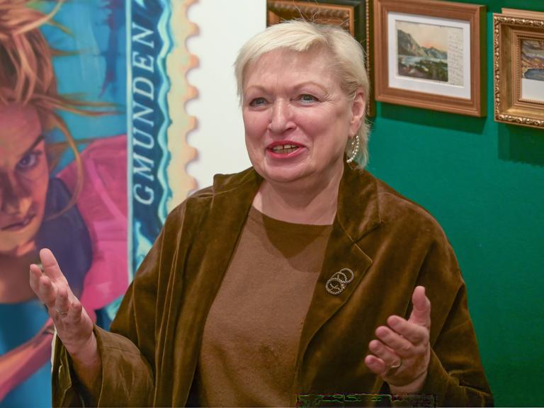 Karin Bergmann breitet die Hände aus und lächelt in die Kamera.