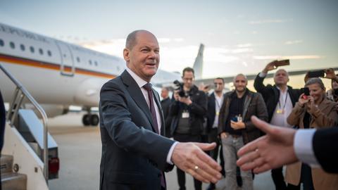 Ein Mann steht vor einem Flugzeug und will eine Hand schütteln.