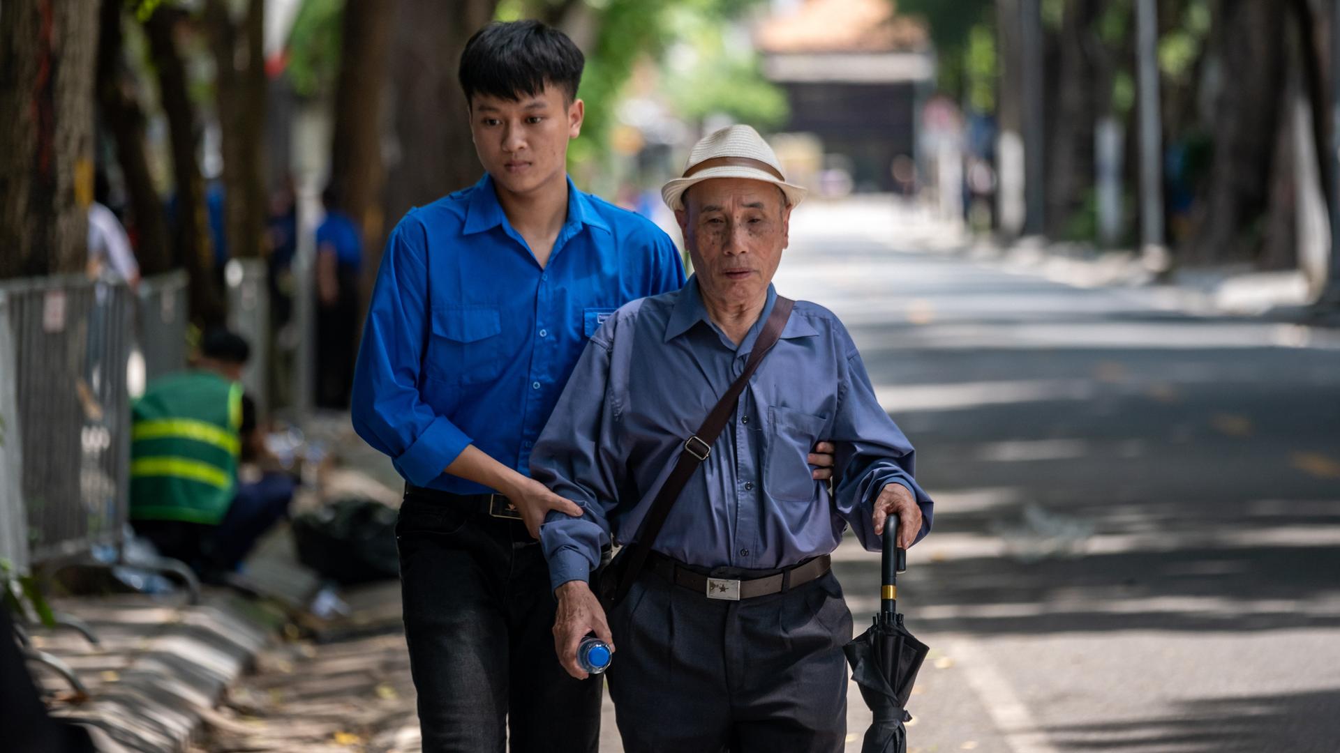 Ein junger Vietnamese hält einen älteren Mann am Arm und hilft ihm auf der Straße. (Symbolbild) Ein junger Vietnamese hält einen älteren Mann am Arm und hilft ihm auf der Straße. (Symbolbild)