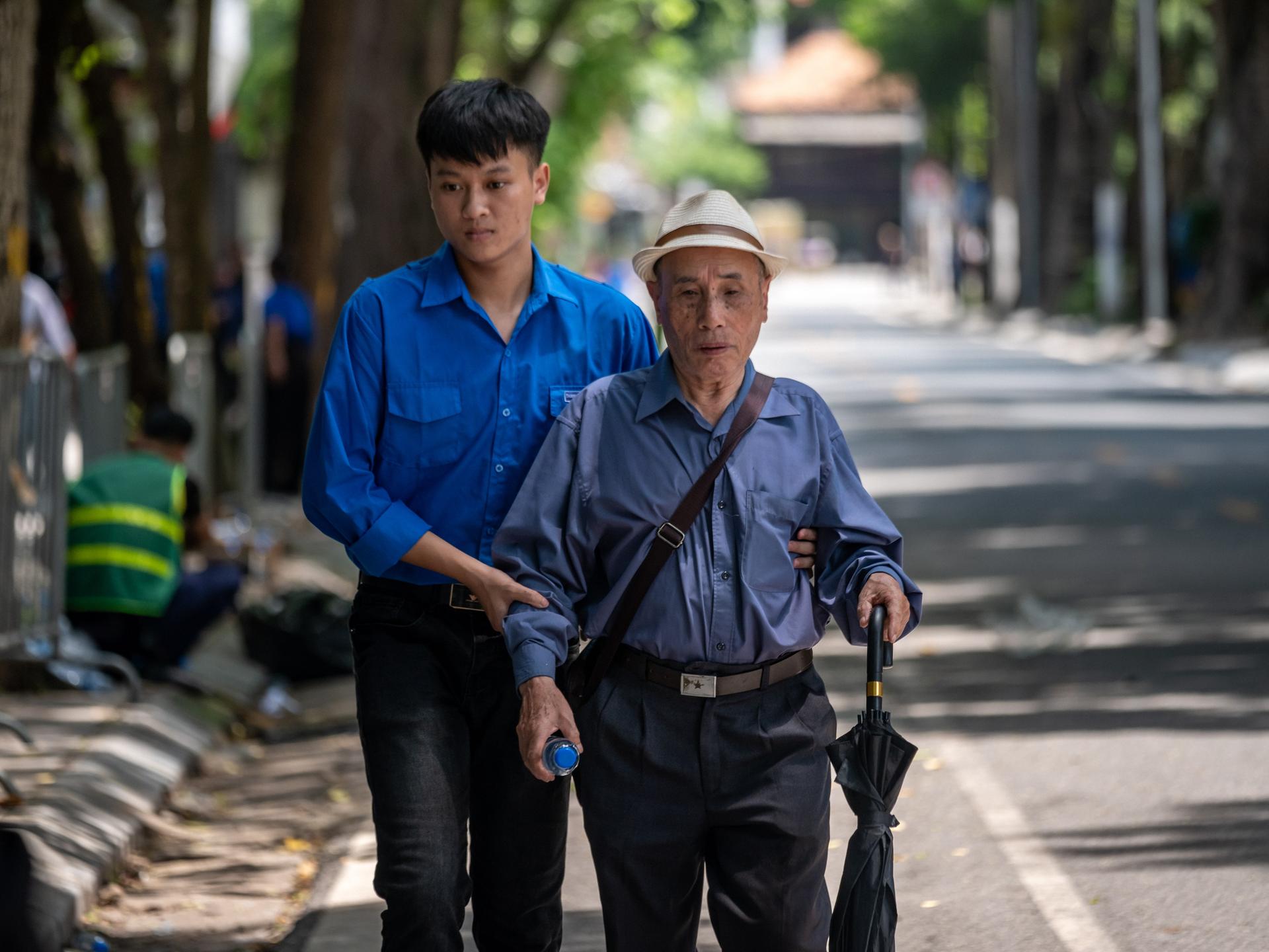 Ein junger Vietnamese hält einen älteren Mann am Arm und hilft ihm auf der Straße. (Symbolbild) Ein junger Vietnamese hält einen älteren Mann am Arm und hilft ihm auf der Straße. (Symbolbild)