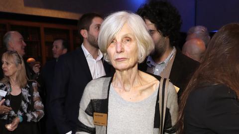 Die britische Autorin Caryl Churchill steht mit einem Getränk in der Hand vor anderen Personen